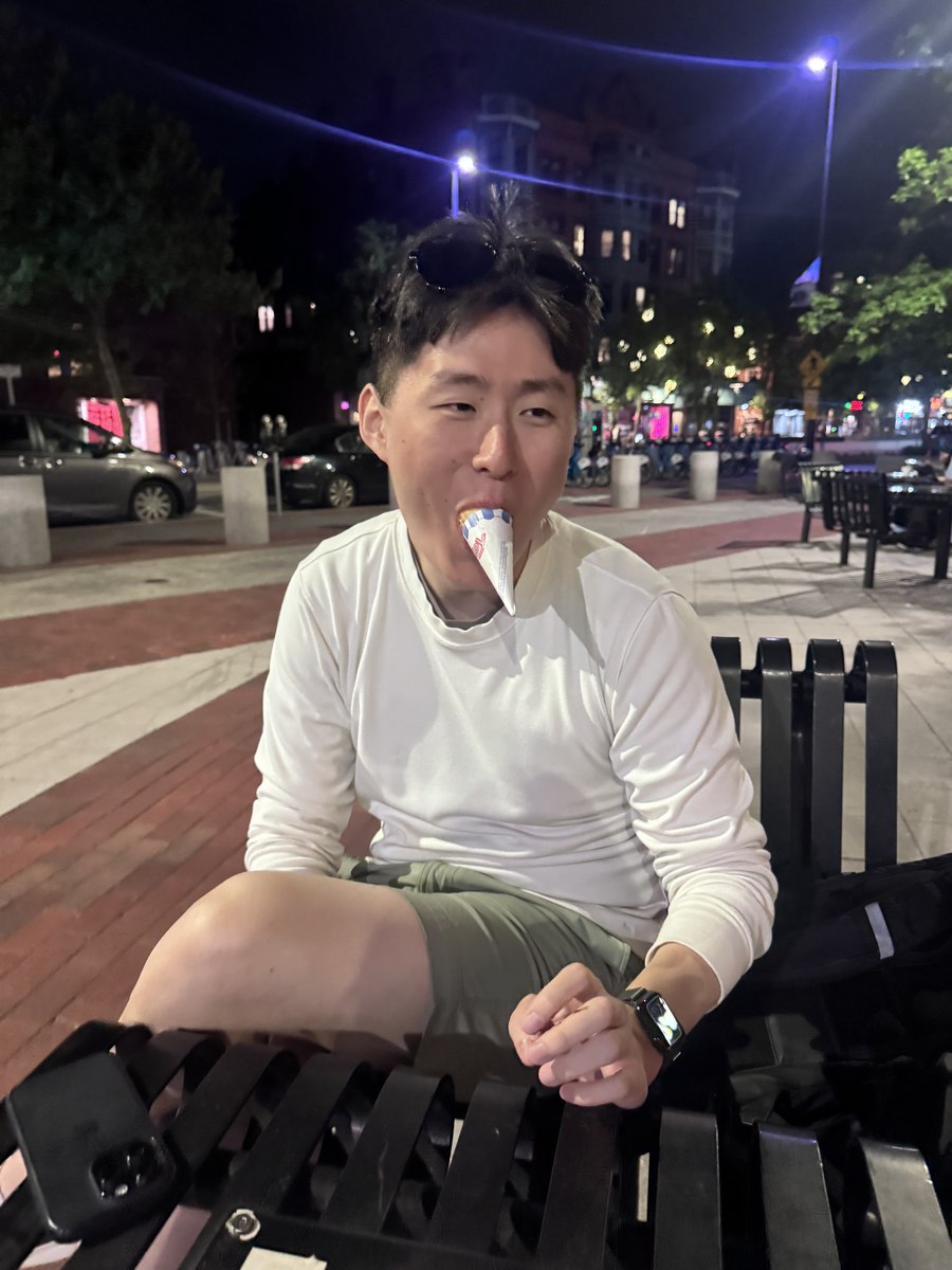 A person seated outdoors at night with an ice cream cone.