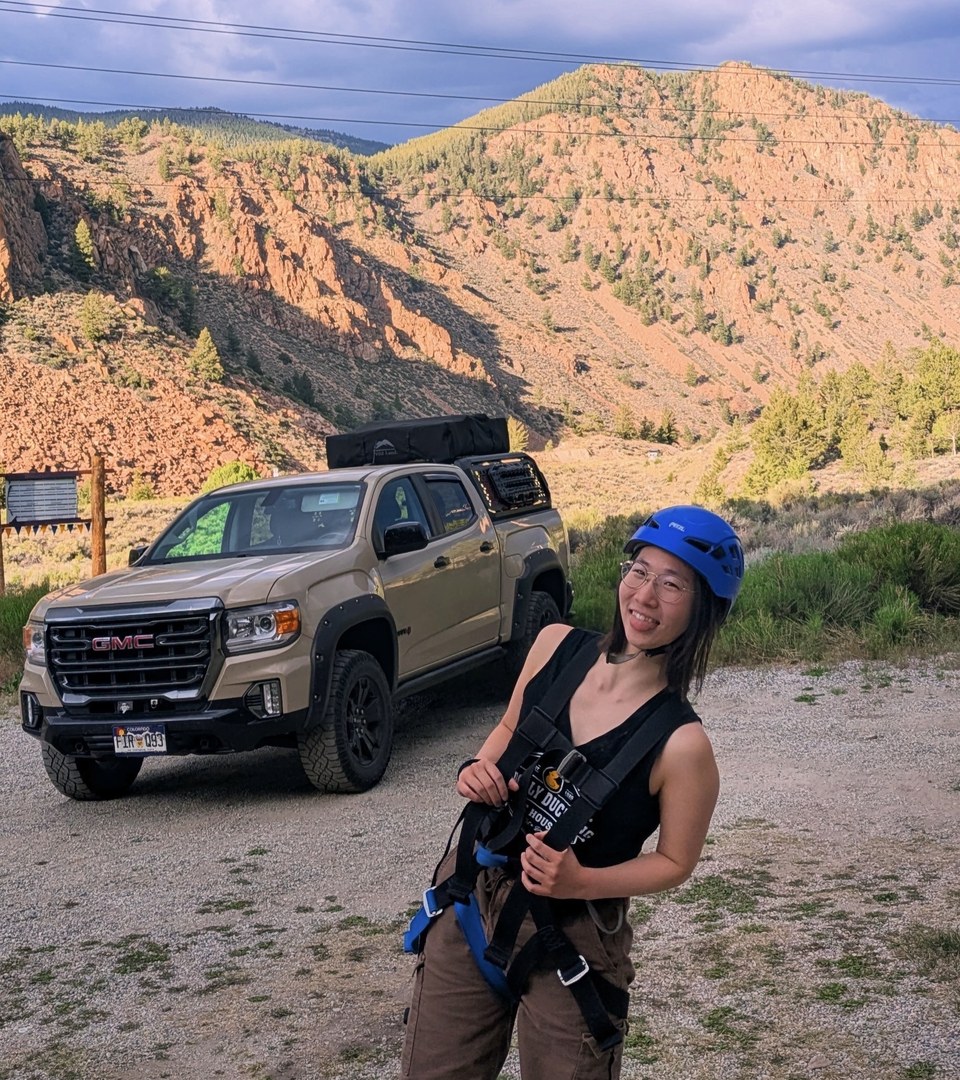 Julia Meng outdoors wearing a blue helmet, with mountains in the background.